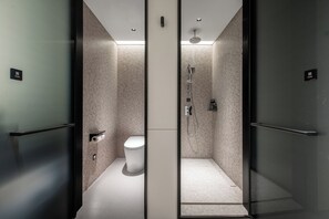 Een moderne badkamer met toilet, douche en glazen douchecabine.