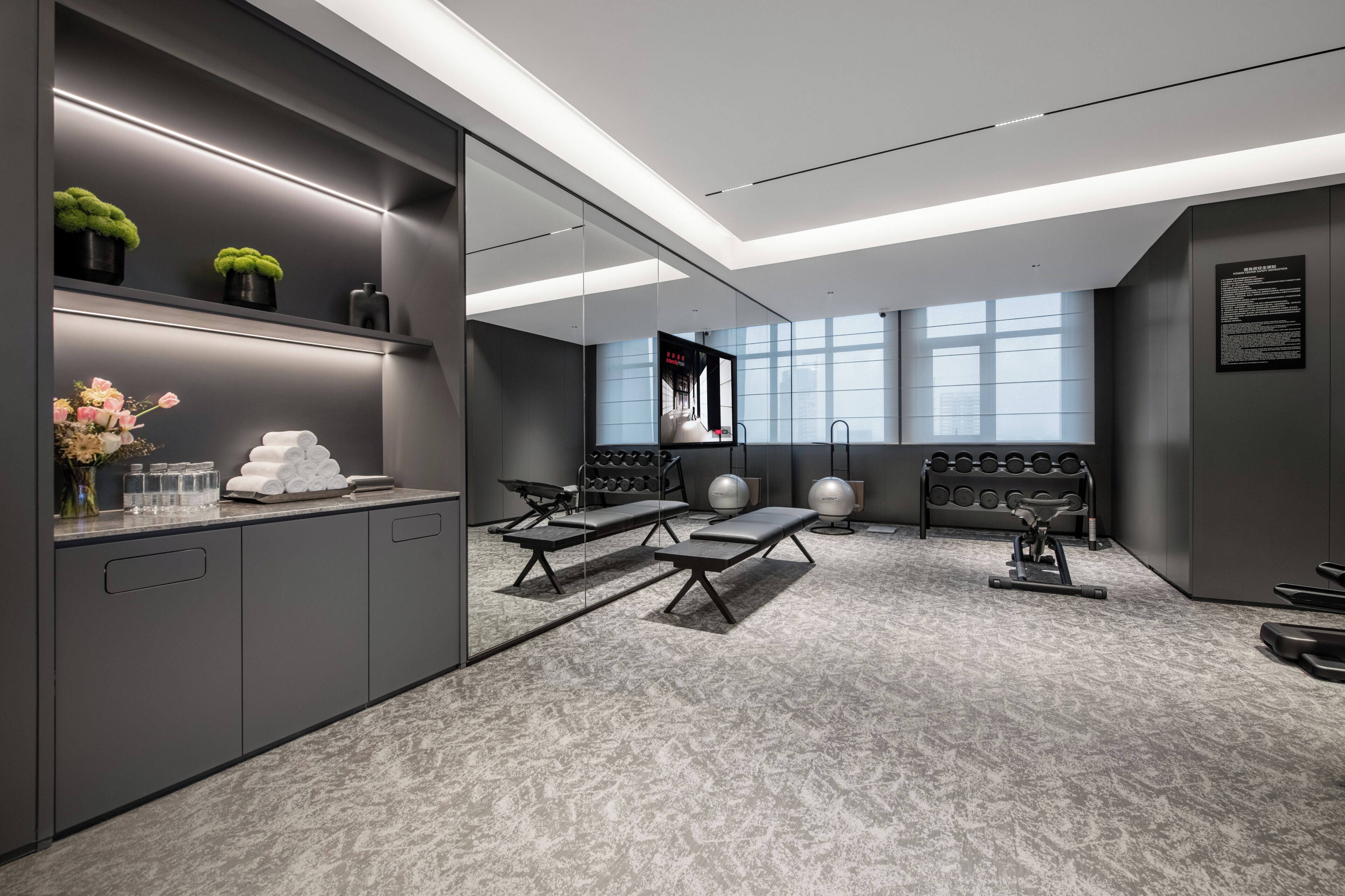 A modern gym with exercise equipment, a mirror, and a large window.