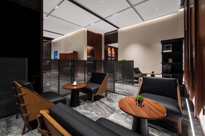 Een moderne lounge met lederen zitplaatsen, een ronde houten tafel en een glazen scheiding.