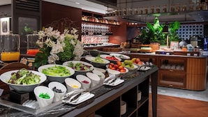 En buffet med forskellige retter, en kaffestation og et barområde med hylder fyldt med flasker.