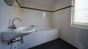 Une salle de bain avec un lavabo, une baignoire et une fenêtre.