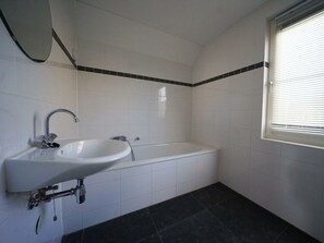 Een badkamer met een wastafel, bad en een raam.