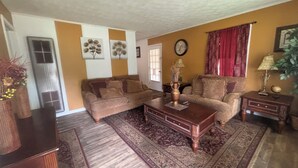 A living room with two sofas, a coffee table, a rug, a clock, and a plant. - Vintage- Getaway Fabulous 3-bedroom house with AC in charming Columbus (Columbus)