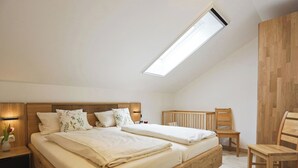 Ein Schlafzimmer mit einem hölzernen Bett, einem Schreibtisch, einem Stuhl und einem Oberlicht.