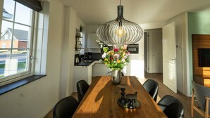 A modern kitchen with a dining area, a large window, and a hanging light fixture. - Watervilla Miva Wellness 6 (Medemblik)