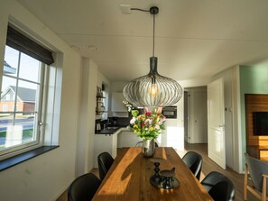 Une cuisine moderne avec un coin repas, une grande fenêtre et un luminaire suspendu.