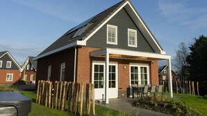 A residential house with a sloped roof, a covered porch, and a brick exterior. - Watervilla Miva Wellness 6 (Medemblik)