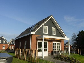 Une maison d’habitation avec un toit en pente, un porche couvert et une façade en briques.