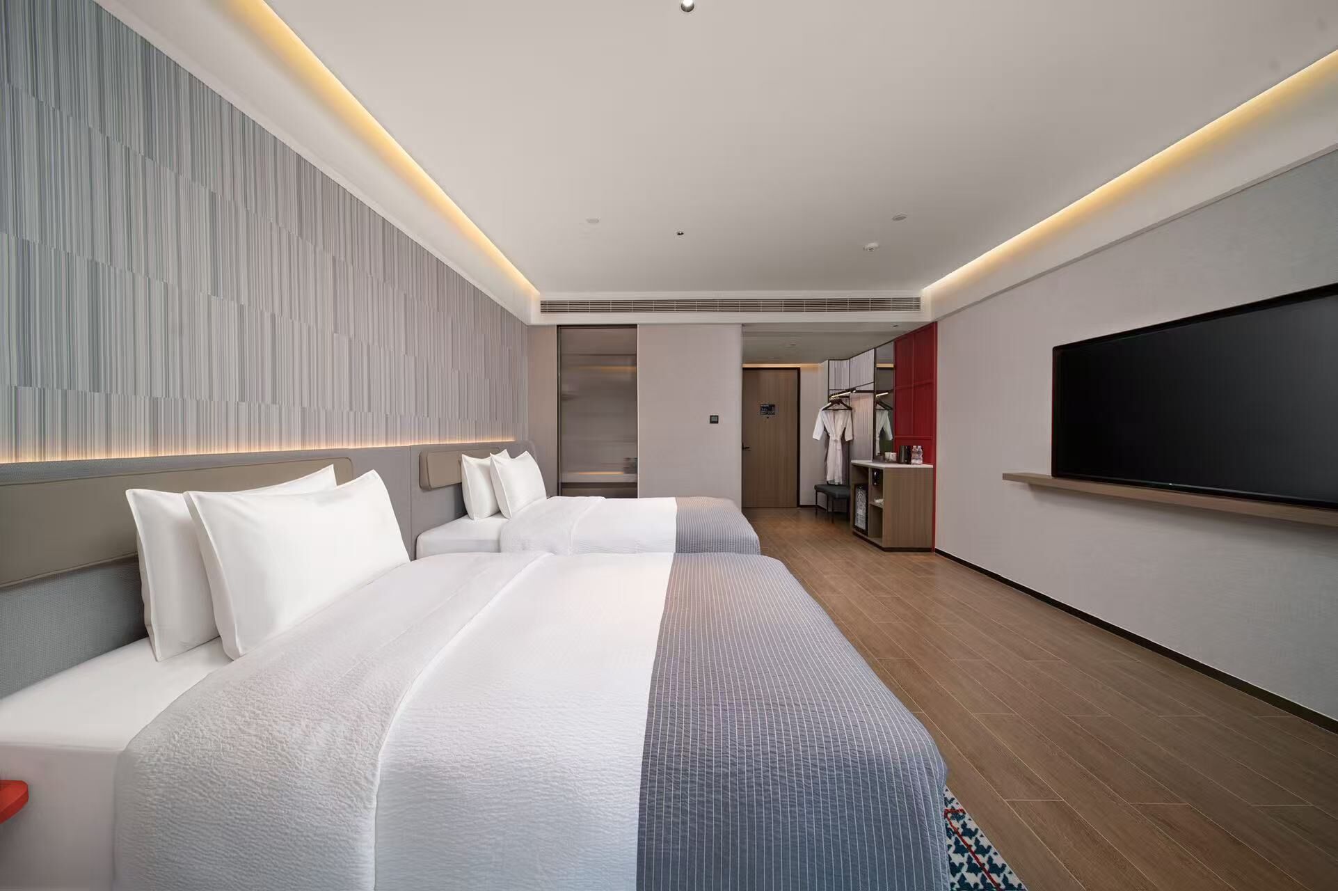 Une chambre d’hôtel moderne équipée d’un grand lit, d’une télévision et d’une kitchenette.