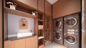 A modern laundry room with built-in washers and dryers, a sink, and a mirror. - Wanda Moments Bengbu south Railway (Bengbu)