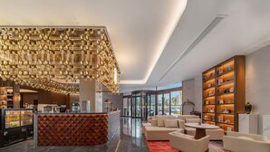 A modern lobby with a geometric light fixture, a reception desk, seating area, and a bookshelf. - Wanda Moments Bengbu south Railway (Bengbu)