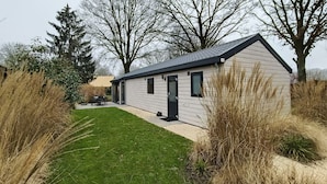 A small, single-story house with a sloped roof, a front door, and a small porch area. - Holiday Home in Kaatsheuvel With Terrace (Kaatsheuvel)