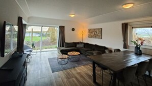A modern living room with a sofa, coffee table, dining table, and chairs. - Holiday Home in Kaatsheuvel With Terrace (Kaatsheuvel)