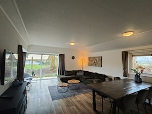 Ein modernes Wohnzimmer mit Sofa, Couchtisch, Esstisch und Stühlen.