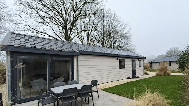 A single-story house with a patio, a dining table with chairs, and a covered outdoor seating area. - Holiday Home in Kaatsheuvel With Terrace (Kaatsheuvel)