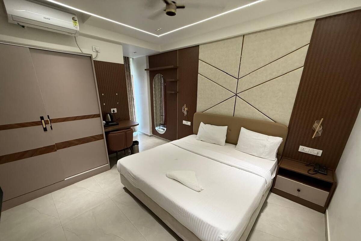 Une chambre d’hôtel avec un grand lit, une armoire, une table de chevet et un miroir.
