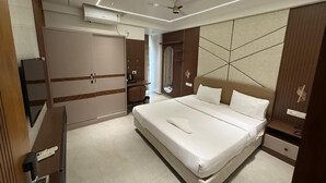 Quarto de hotel moderno com cama grande, roupeiro embutido, escrivaninha e espelho.