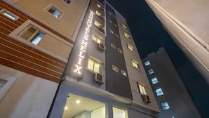 Een meerhoog hotel met verlichte signage, airconditioning units en een modern architectonisch ontwerp.