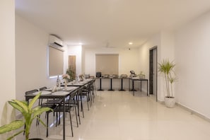 A modern kitchen with a long countertop, a dining area with a table and chairs, and a potted plant. - RCC Hotels Helix Gachibowli (Hyderabad)