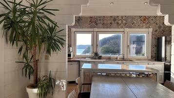 A kitchen with a large window, a dining table, chairs, and a potted plant.
