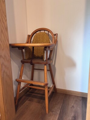 A wooden high chair with a seat cushion against a wall. - Peaceful 4-bedroom house just outside Wisconsin Dells (Wisconsin Dells)