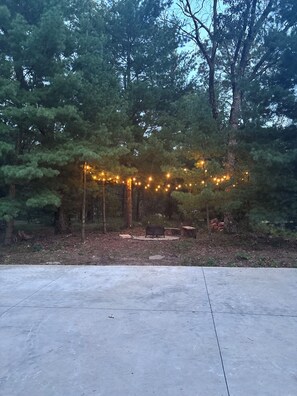 Eine Beton-Terrasse mit Lichterkette und Gartenmöbeln.