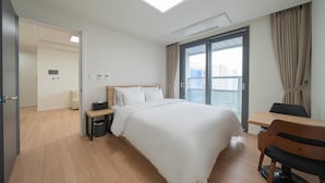 A hotel room with a bed, bedside table, chair, and a window with curtains.