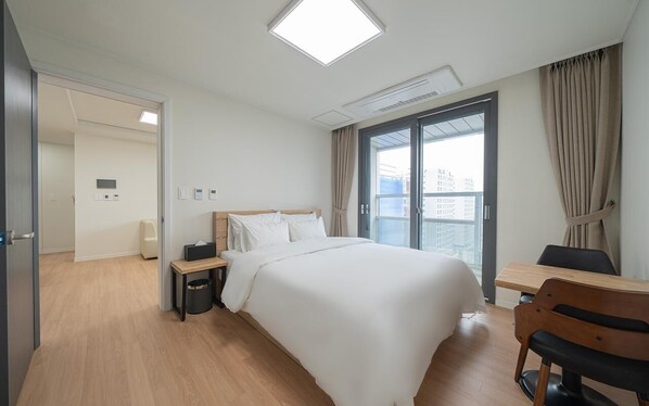 Une chambre d’hôtel avec un lit, une table de chevet, une chaise et une fenêtre avec des rideaux.
