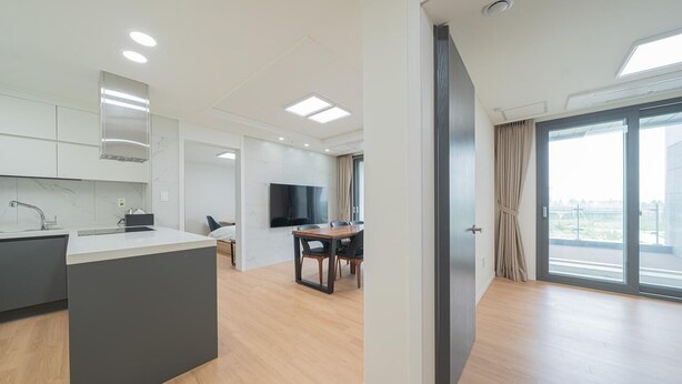 A modern apartment with a kitchen, dining area, and a balcony with a view.