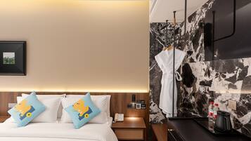 A hotel room with a bed, bedside table, nightstand, robe, and a coffee maker.