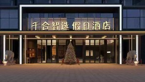 Entrada de hotel con un gran letrero iluminado, un árbol de Navidad y dos estatuas de elefantes.