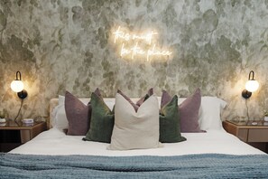 A bedroom with a textured wall, a bed with multiple pillows, bedside lamps, and a neon sign. - Luxury Scottsdale Retreat / Pool, Games, BBQ & Sleeps 10+ (Scottsdale)
