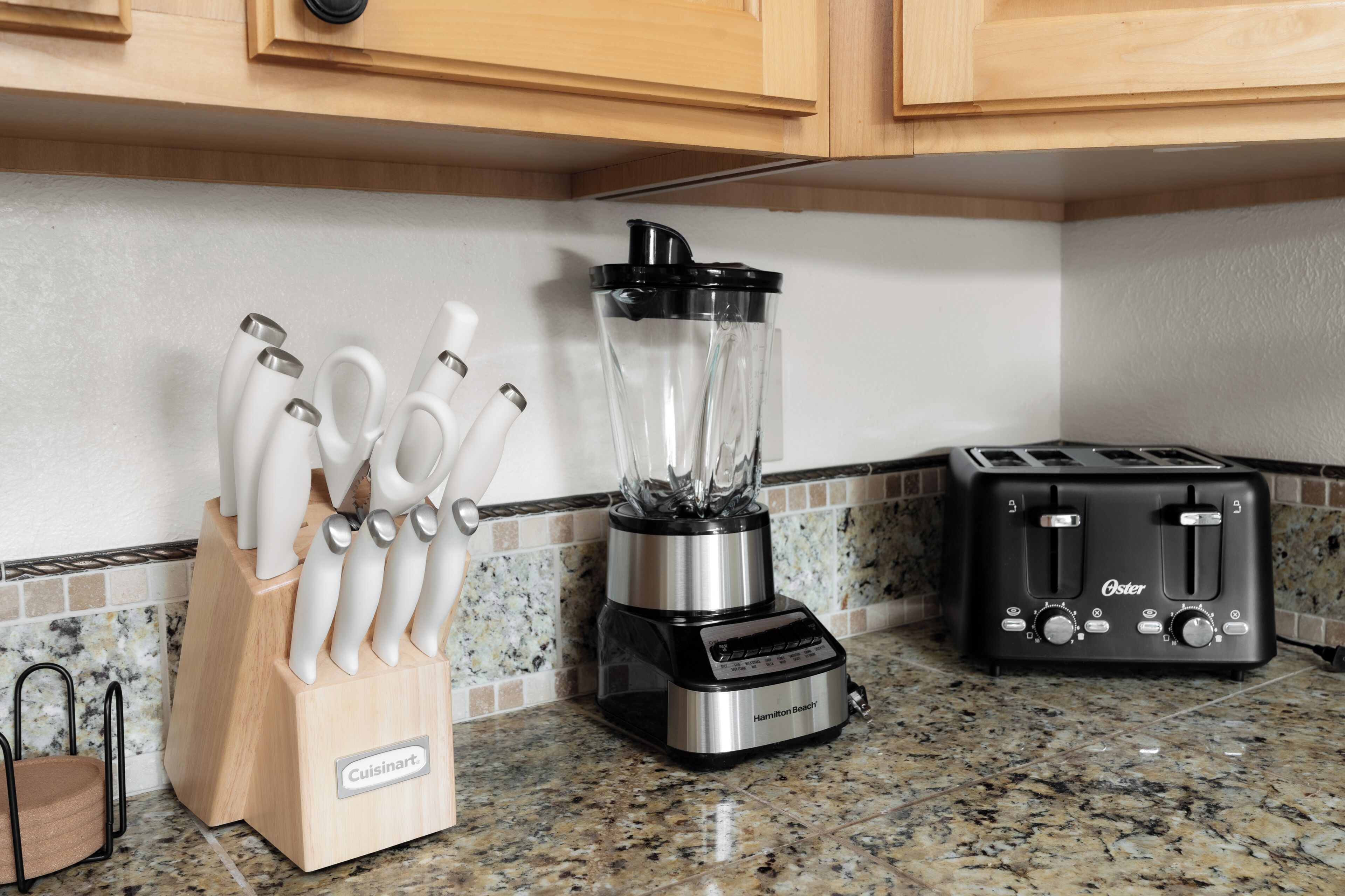 A kitchen with a blender, a toaster, and a knife block.