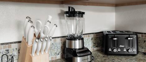 A kitchen with a blender, a toaster, and a knife block.