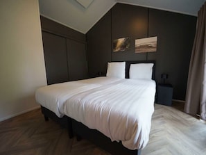 Ein modernes Schlafzimmer mit einem großen Bett, dunklen Wänden und zwei Wandbildern.