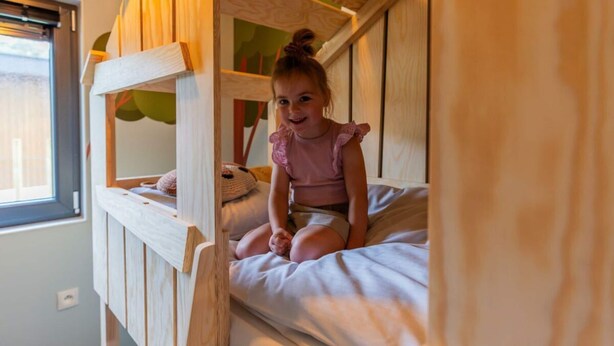 Una cama litera con un niño sentado en la cama inferior.
