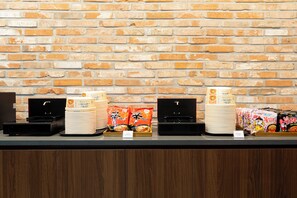 A buffet setup with food items and serving equipment against a brick wall.