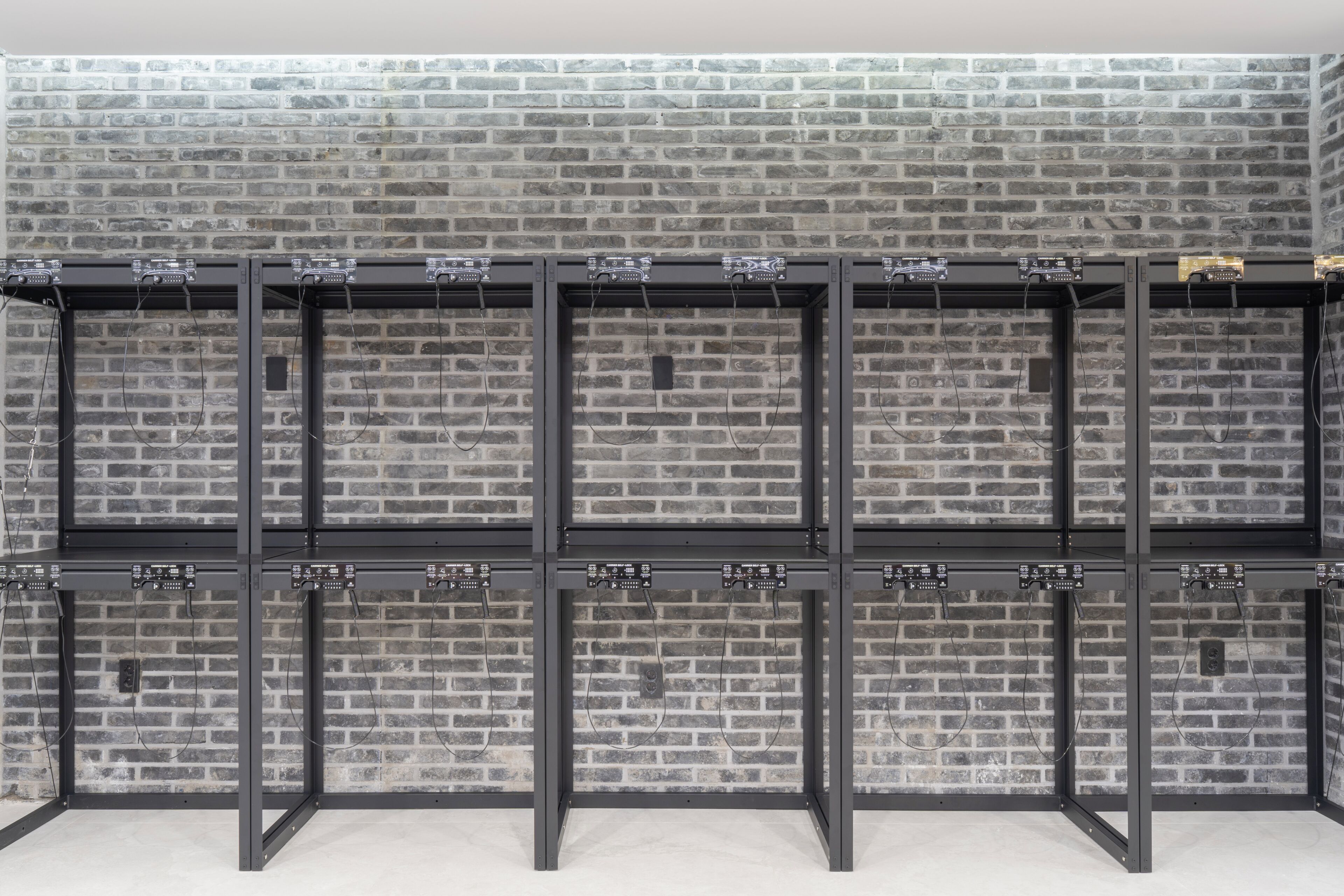 A brick wall with metal shelving units against it.