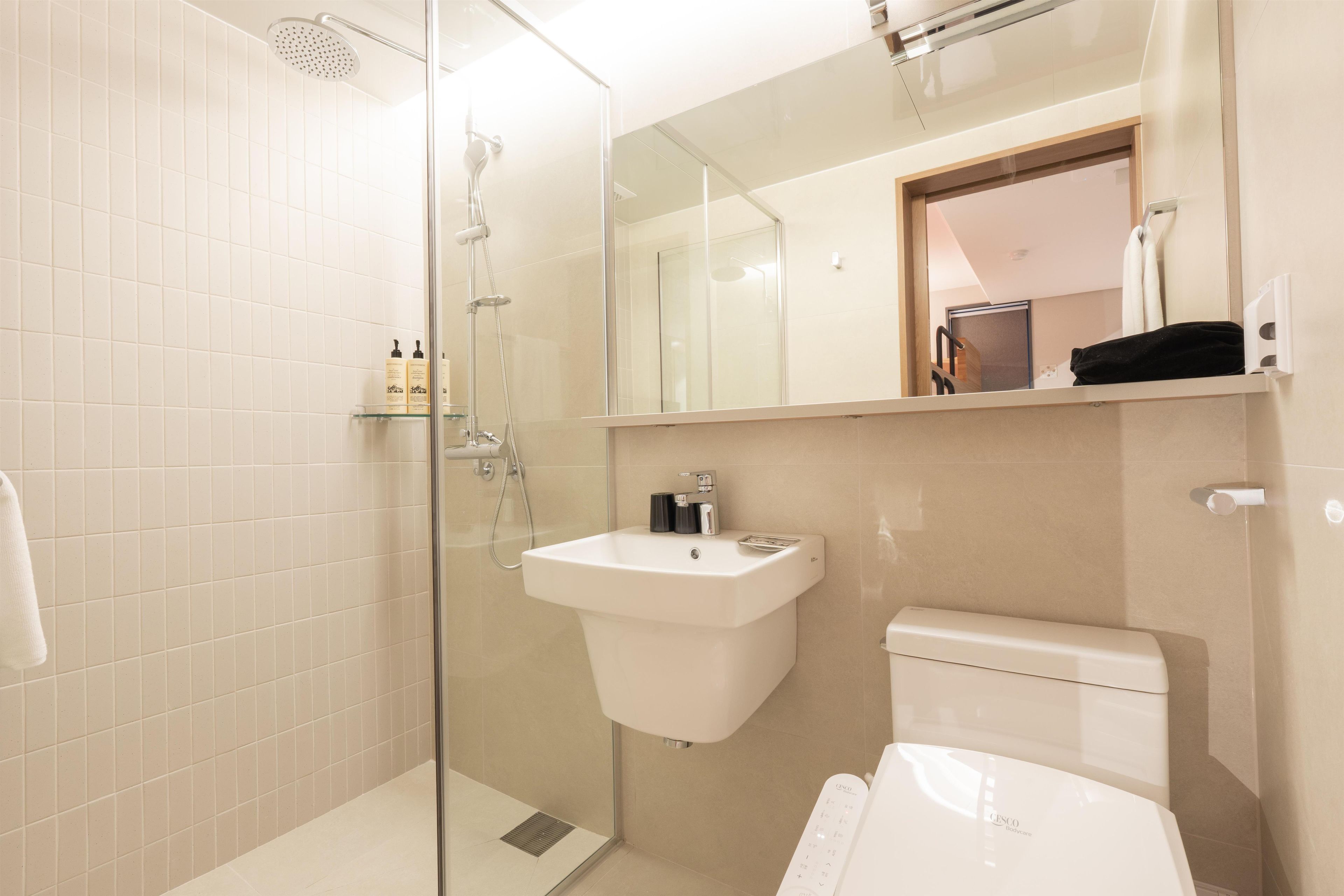 A modern bathroom with a glass-enclosed shower, a white sink, and a toilet.