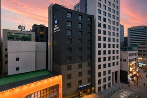 Un hotel de varios pisos con un llamativo letrero de 'Best Western', ventanas amplias y una terraza en la azotea.
