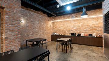 A brick-walled room with a bar area, tables, and chairs.
