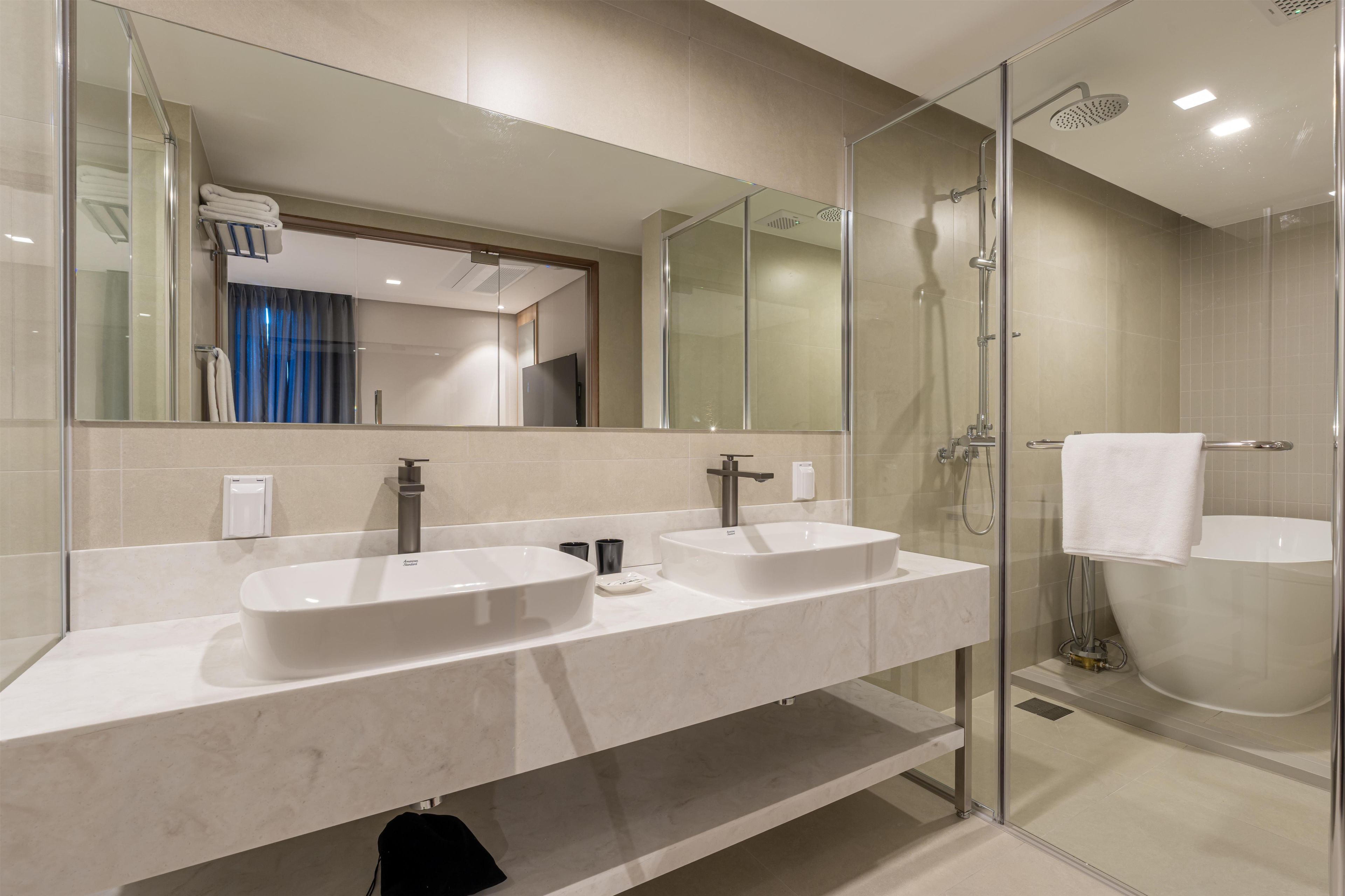 A modern bathroom with a glass-enclosed shower, two sinks, and a large mirror.