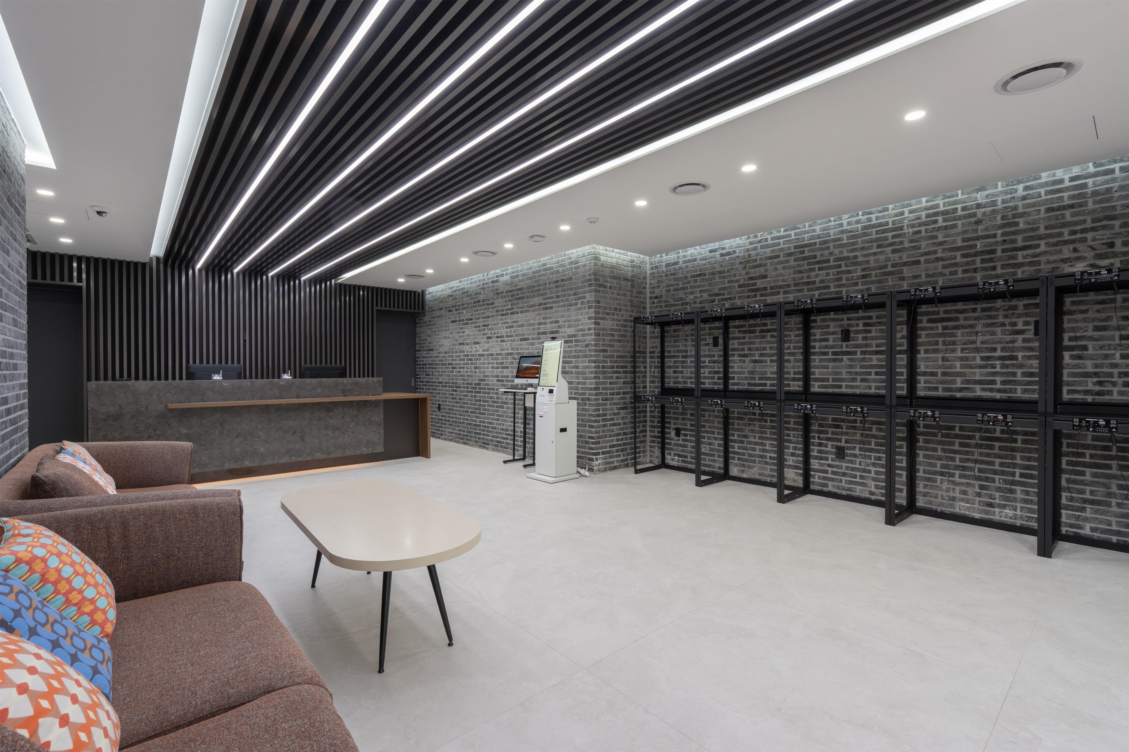 A modern lobby with a reception desk, seating area, and a wall-mounted server rack.