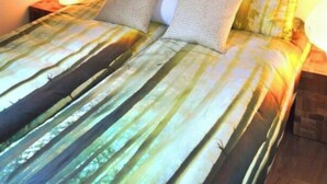 A bed with a striped bedspread, two pillows, a nightstand with a lamp, and a framed picture above the bed. - Holiday Home in Breskens With Terrace (Breskens)