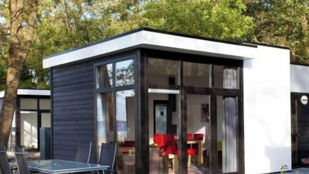 A modern, glass-walled structure with a minimalist design, featuring a dining area with a table and chairs. - Holiday Home in Breskens With Terrace (Breskens)