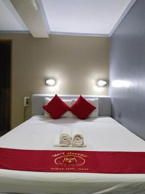 Ein Hotelzimmer mit einem Bett, zwei roten Kissen, einer roten Tagesdecke und einer Handtuchgestaltung.