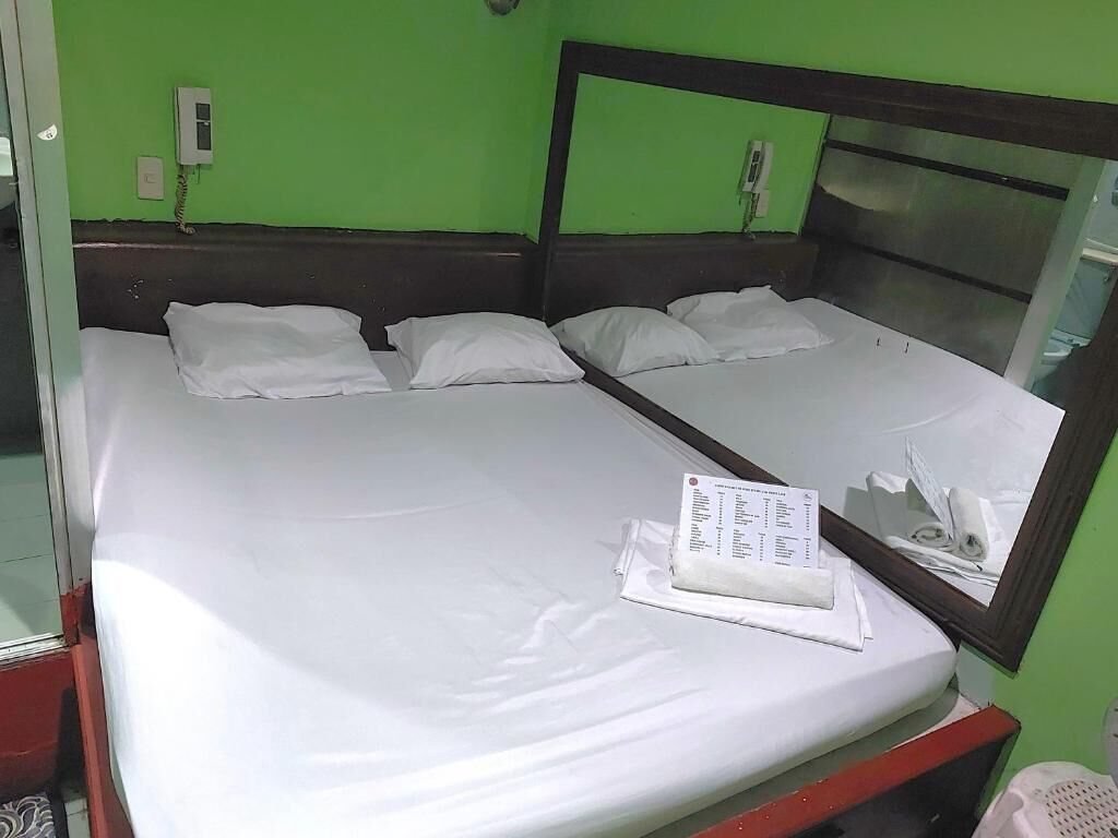 A double bed with white bedding, a mirror, and a wall-mounted phone.
