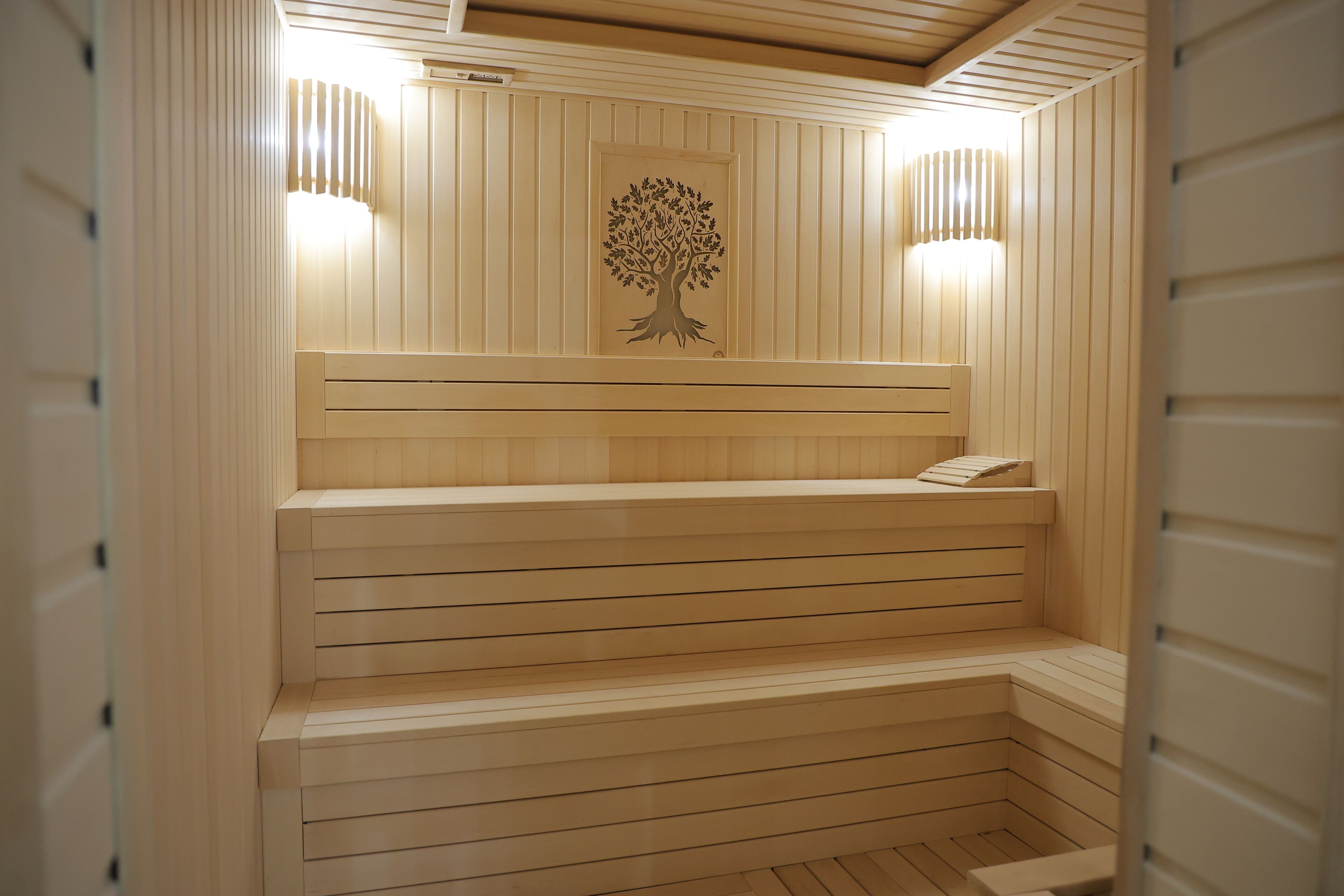 A sauna with wooden benches and a tree mural on the wall.