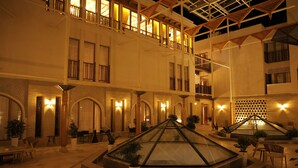 Un vestíbulo de hotel de varios niveles con una pirámide de cristal central, múltiples balcones e iluminación cálida.