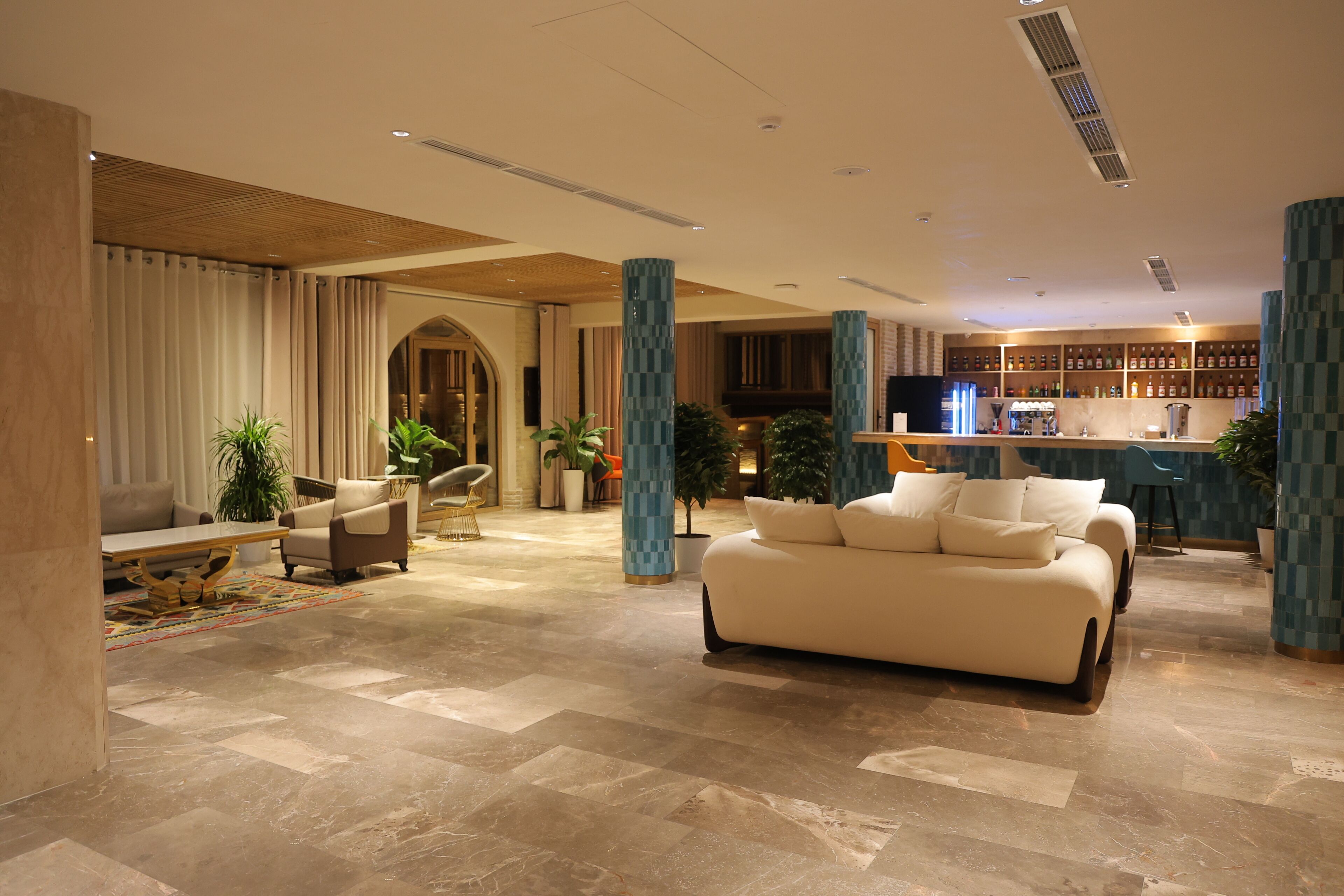A spacious lobby with a large sofa, a bar area, and a seating area with chairs and a table.